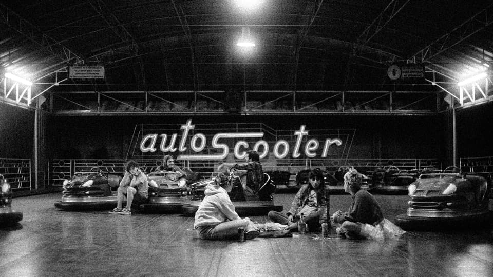 Grupo de jóvenes sentados en una pista de autos chocadores